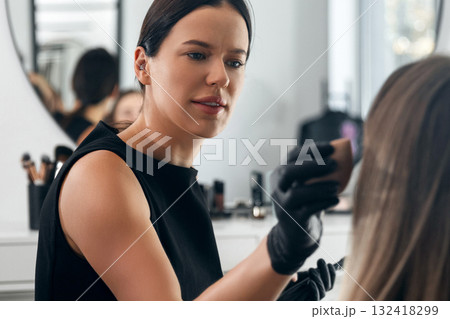 Makeup artist applying foundation to client in modern beauty studio during morning hours Makeup artist applying foundation to client in modern beauty studio during morning hours 132418299