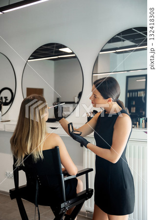 Makeup artist applying makeup to a client in a modern beauty salon during the day Makeup artist applying makeup to a client in a modern beauty salon during the day 132418308