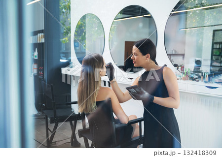 Beauty specialist applying makeup to client in modern salon during daytime Beauty specialist applying makeup to client in modern salon during daytime 132418309