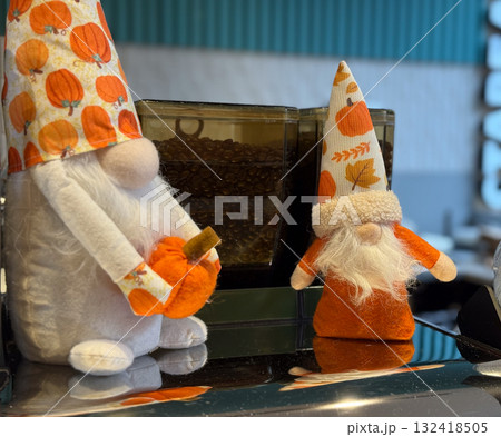 Two autumn gnome decorations with pumpkin patterns and white beards. Cozy seasonal display, festive cafe atmosphere and warm handcrafted charm celebrating the spirit of fall. Two autumn gnome decorations with pumpkin patterns and white beards. Cozy seasonal display, festive cafe atmosphere and warm handcrafted charm celebrating the spirit of fall. 132418505