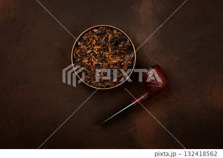 Tin of coarse cut tobacco and pipe over brown 132418562