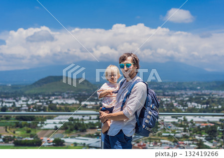 Father and his little son standing together in front of Popocatepetl volcano surrounded by clouds, enjoying a peaceful and heartwarming family travel moment in Mexico 132419266