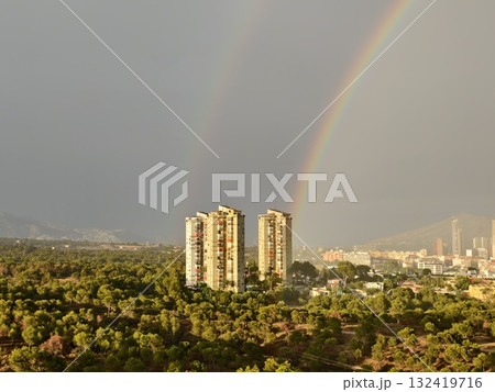 colorful rainbows adorn twin towers, lush park features rainbows and city skyline with twin towers 132419716