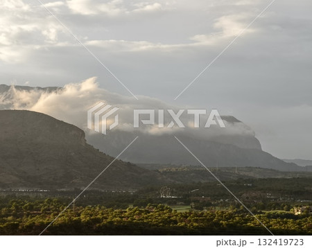 serene dawn over green valley, morning clouds cascade over sandstone cliffs into sunlit valleys 132419723