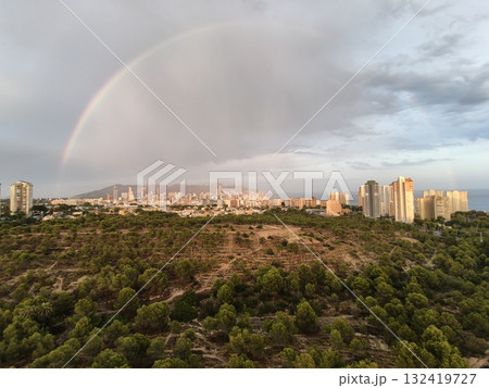 calm evening with rainbow over city hills, soft rainbow casts glow on misty city and countryside calm evening with rainbow over city hills, soft rainbow casts glow on misty city and countryside 132419727