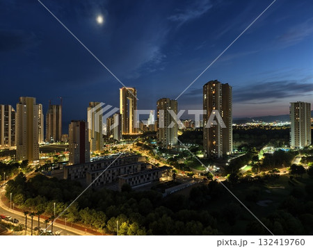 urban night with moonlight, moonlit highrise skyline with clouds and illuminated office windows urban night with moonlight, moonlit highrise skyline with clouds and illuminated office windows 132419760
