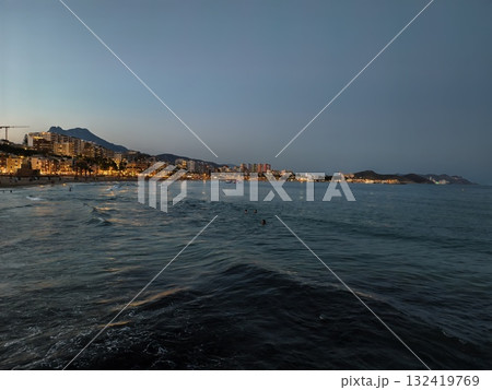 calm bay with city reflections, tranquil dusk by bay with mountain silhouette and glowing calm bay with city reflections, tranquil dusk by bay with mountain silhouette and glowing 132419769