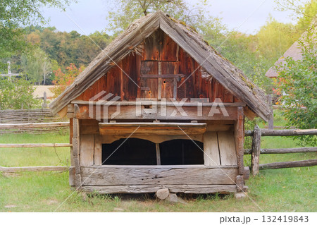 Aged wooden peasant house. Retro roof. Ancient countryside house for feeding domestic animals. Sunny day. Aged wooden peasant house. Retro roof. Ancient countryside house for feeding domestic animals. Sunny day. 132419843