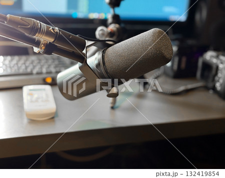 Studio microphone on desk with blurred background and soft lighting. Sound recording, podcast production and creative workspace for voice and music creation. 132419854