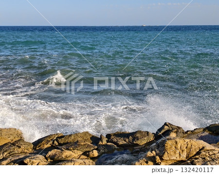dynamic ocean spray over rugged stones, energetic ocean wave crashing onto jagged coastal rocks dynamic ocean spray over rugged stones, energetic ocean wave crashing onto jagged coastal rocks 132420117