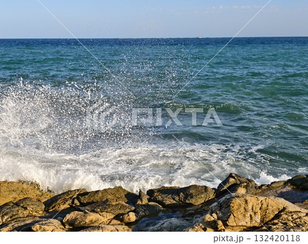 gentle waves on rocks, soothing coastal scene with retreating foamy surf and steady horizon gentle waves on rocks, soothing coastal scene with retreating foamy surf and steady horizon 132420118