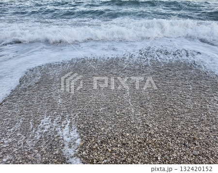 serene beach setting featuring rhythmic wave motion and contrasting pebble textures at shoreline 132420152