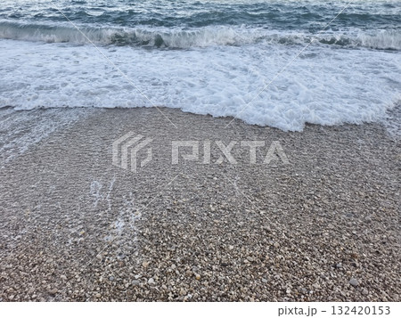 closeup of retreating wave and pebbles, coastal retreating wave exposes sparkling pebbles and frothy closeup of retreating wave and pebbles, coastal retreating wave exposes sparkling pebbles and frothy 132420153