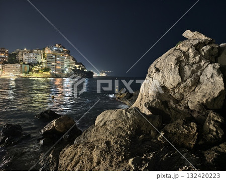 night city reflections on calm water, peaceful nighttime coastal view with illuminated city 132420223