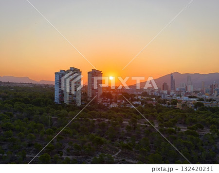 captivating drone shot of evening sun sinking behind urban apartment blocks with dramatic sky captivating drone shot of evening sun sinking behind urban apartment blocks with dramatic sky 132420231