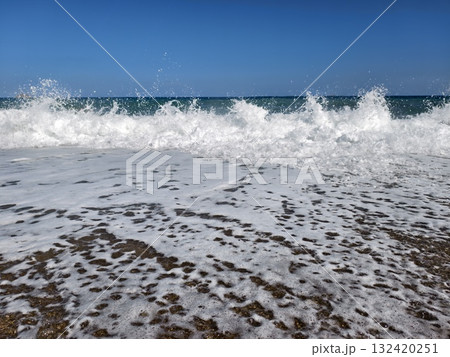 dynamic coastal scene, powerful waves hitting sandy coast, foaming waves crash onto beach shore 132420251