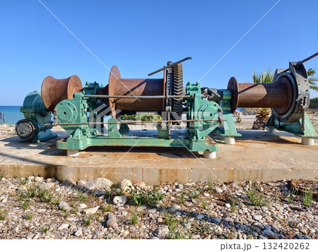 corroded machinery on harbor platform, decayed machinery and cables at seaside harbor under bright corroded machinery on harbor platform, decayed machinery and cables at seaside harbor under bright 132420262