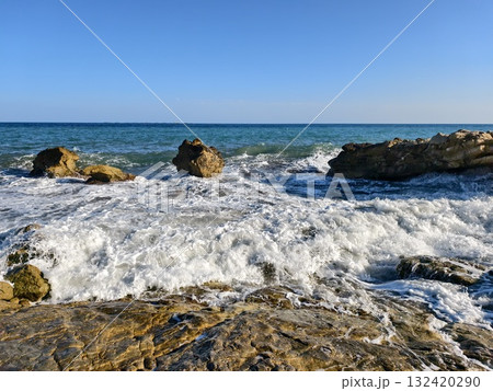 calm sea with rocks and horizon view, gentle ocean waves reach rocky shoreline under distant sky 132420290