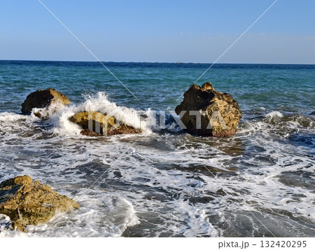 seascape with rocks, twin rocky formations amidst dynamic ocean waves and vibrant spray scene 132420295