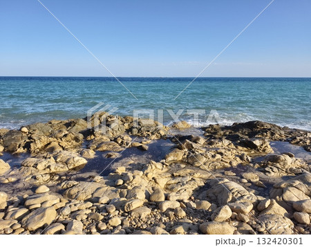 calm azure waters and sunlit stones scene, peaceful seaside landscape with smooth rocks and serene 132420301