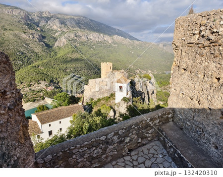 ancient stone fortress perched above emerald reservoir with sweeping hillside views and heritage 132420310