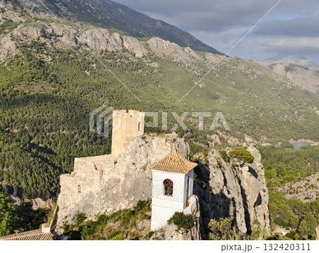 crumbling cliffside chapel adjacent to ancient fortress overlooking ravine with panoramic mountain 132420311