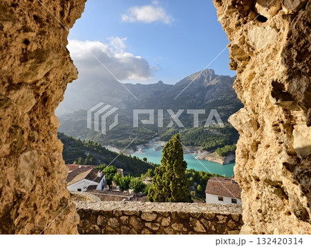 arch frames mountain lake scene, natural stone arch overlooking distant peaks and tranquil village arch frames mountain lake scene, natural stone arch overlooking distant peaks and tranquil village 132420314