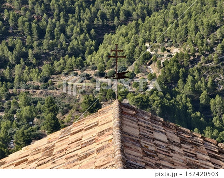 terracotta roof view, terracottatiled roof and metal cross overlooking green valleys and slopes terracotta roof view, terracottatiled roof and metal cross overlooking green valleys and slopes 132420503