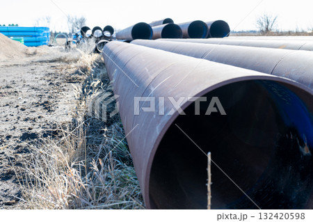 Metal pipes lined up on the ground in a construction site during a clear daylight in an industrial area Metal pipes lined up on the ground in a construction site during a clear daylight in an industrial area 132420598