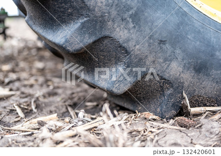 Close view of large tractor tire on muddy ground at a rural farm during autumn harvest time Close view of large tractor tire on muddy ground at a rural farm during autumn harvest time 132420601