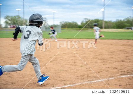 Young athlete runs towards home plate during a baseball game in a city park on a cloudy afternoon 132420611