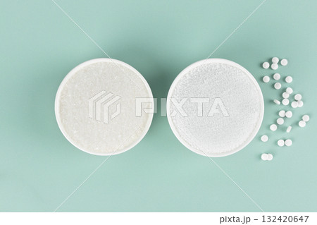 Two bowls: sugar and natural sweetener stevia on a blue background. Weight loss concept. Top view. Two bowls: sugar and natural sweetener stevia on a blue background. Weight loss concept. Top view. 132420647