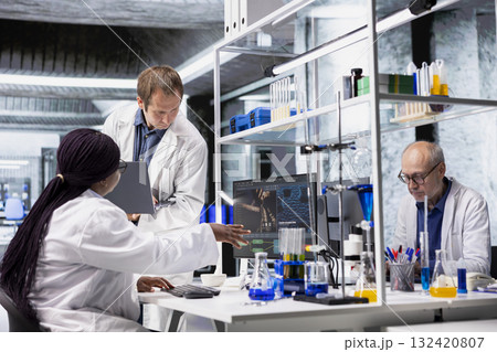 Team of diverse experts work on diagnostics and testing procedures. Doing scientific work to combine molecular biology, genetics research and research with modern lab equipment. 132420807