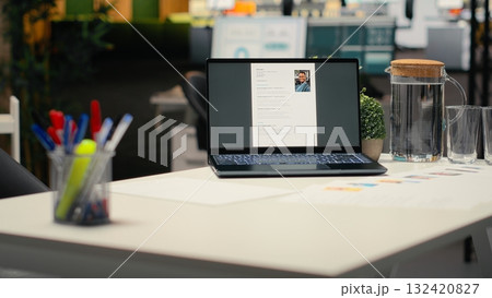 Laptop in empty corporate space shows applicant CV before hiring interview, office used for the recruitment process and reviewing qualifications or work experience to align with position. Laptop in empty corporate space shows applicant CV before hiring interview, office used for the recruitment process and reviewing qualifications or work experience to align with position. 132420827