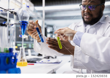 Close up of lab coworkers inspecting liquids in test tube, looking for breakthroughs during clinical trials. Team of specialists in research facility comparing chemicals vials, testing right formula 132420838