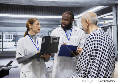 Diverse scientists performing observation and examination of a patient in a research lab, testing a new treatment and analyzing dosage effects. Studying risks and outcomes for progress. 132420895