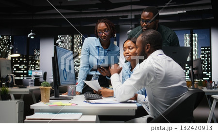 African american team of employees working late on goal setting, studying data insights and performance metrics. Colleagues creating reports for business administration, strategy room. 132420913