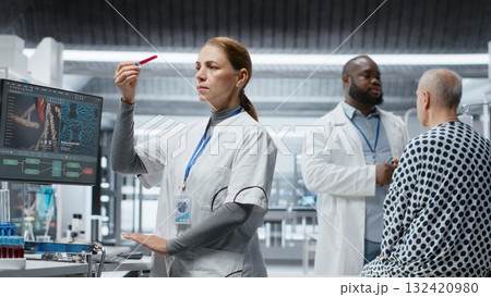 Female doctor checks blood samples from patient during clinical trial, monitoring vitals, dosage reactions and treatment progress. Woman works on advancing healthcare science. Camera B. Female doctor checks blood samples from patient during clinical trial, monitoring vitals, dosage reactions and treatment progress. Woman works on advancing healthcare science. Camera B. 132420980