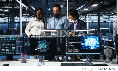 Happy data center coworkers monitoring neural network AI LLM visualization. Jolly workers in high tech facility using devices to oversee servers powering machine learning processes, camera A 132421075
