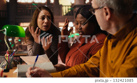 Diverse actors rehearsing dialogue and character expression in a quiet library, studying classic drama play lines with discipline and commitment. Theatre performance practice. Diverse actors rehearsing dialogue and character expression in a quiet library, studying classic drama play lines with discipline and commitment. Theatre performance practice. 132421085