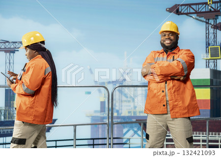 Portrait of smiling technician inspecting integrity of offshore platform components to avoid downtime. Jolly man on drilling rig deck using diagnostic tools to detect malfunction in subsea pipelines 132421093