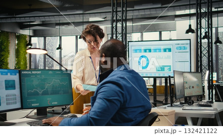 Workplace support employee moves a delivery cart stacked with folders and contracts, helping african american administrator bringing stack of archived documents for accounting tasks. Workplace support employee moves a delivery cart stacked with folders and contracts, helping african american administrator bringing stack of archived documents for accounting tasks. 132421122