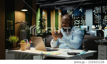 African american person tearing up a paper page after making a mistake, handwriting and notetaking after hours. Frustrated angry employee redoing the draft on a new sheet. 132421126