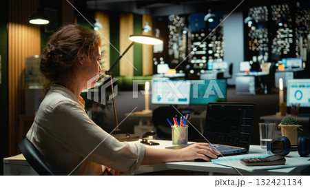 Business professional studies candlestick charts and forex data in office late at night, applying finance insights and economic analysis to develop strategy and organizational growth. Camera A. Business professional studies candlestick charts and forex data in office late at night, applying finance insights and economic analysis to develop strategy and organizational growth. Camera A. 132421134