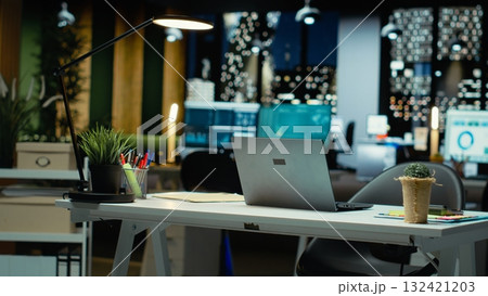 Modern empty office glows with the light of performance metrics and forecasting graphs. Corporate space equipped with technology and computers reflects administration of enterprise objectives. 132421203