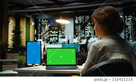 Business consultant works with mockup copy space on tablet and laptop, researching reports for a management project. Collecting information and solving tasks late at night, work after hours. Camera A. 132421213