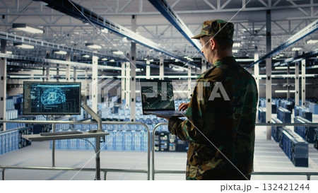 Military engineer in data center tracking satellite coordinates using laptop interface. Soldier in server room analyzing reconnaissance data through satellite imaging systems, camera A 132421244