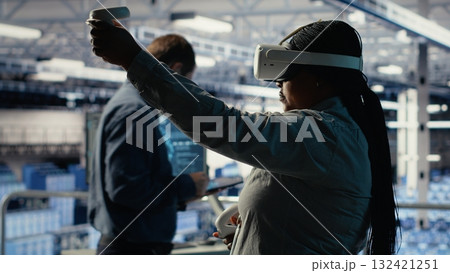 Software developer in server room wearing VR goggles optimizing deep learning systems handling tasks. African american woman in data center adjusts AI model parameters using virtual reality, camera B Software developer in server room wearing VR goggles optimizing deep learning systems handling tasks. African american woman in data center adjusts AI model parameters using virtual reality, camera B 132421251