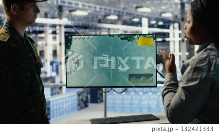 Military data center coworkers looking at radar software on screen to watch for enemy threats. Team of army employees in data center scans suspicious activity to detect dangers, camera B Military data center coworkers looking at radar software on screen to watch for enemy threats. Team of army employees in data center scans suspicious activity to detect dangers, camera B 132421333