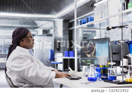Black woman working in biotechnology lab surrounded by modern equipment. Conducting research study for genetics, nanotechnology and healthcare data, supporting pharmaceutical science. 132421452